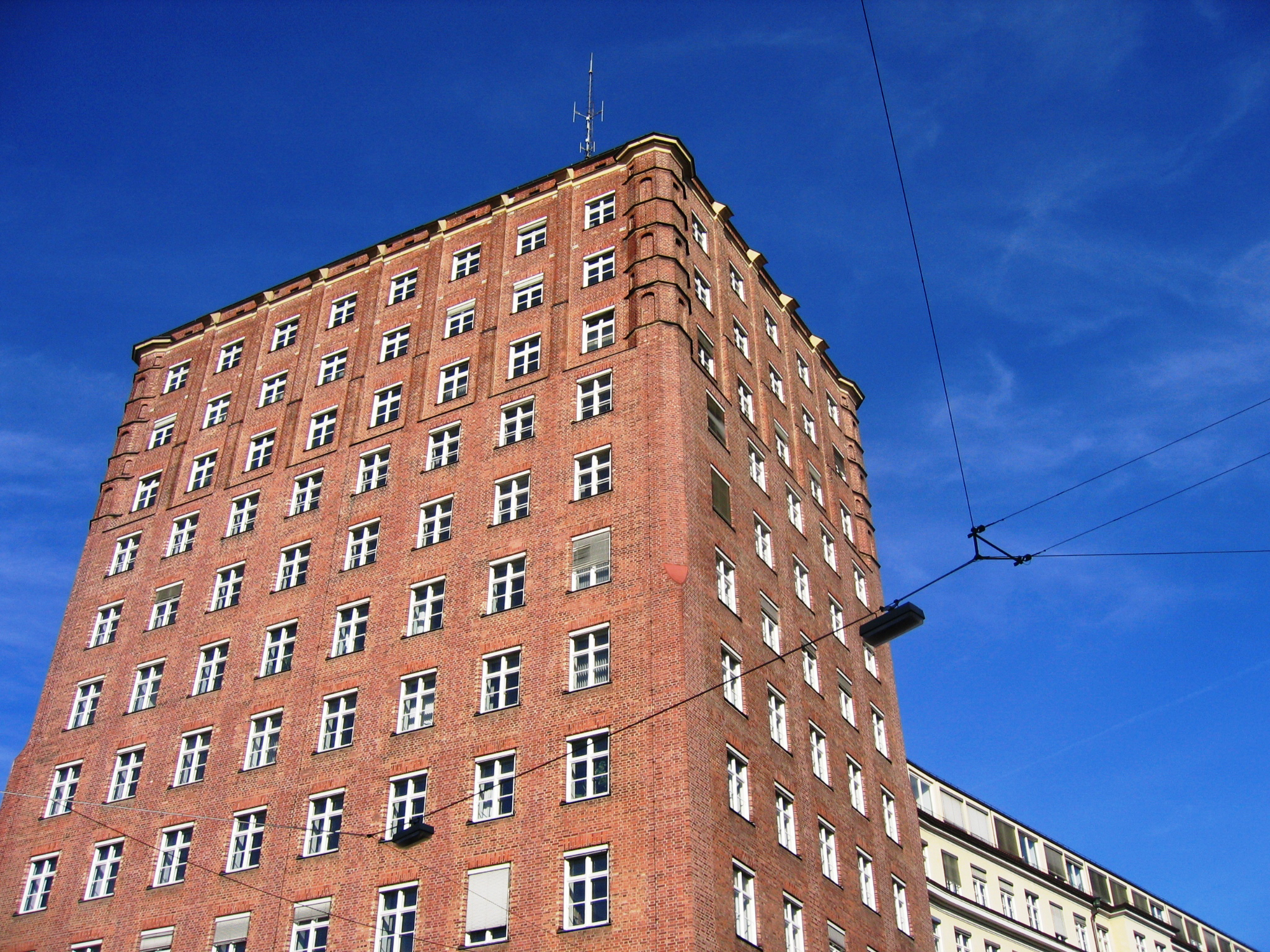Ein altes Backsteingebäude mit vielen Stockwerken vor blauem Himmel